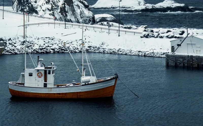 Fischkutter vor verschneiter Lofoten-Küste