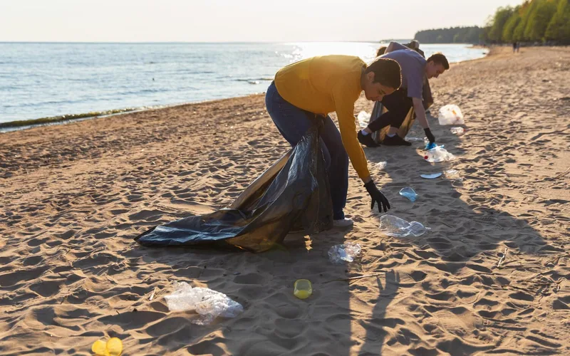 Strandreinigung — Freiwillige sammeln Plastikmüll an der Küste