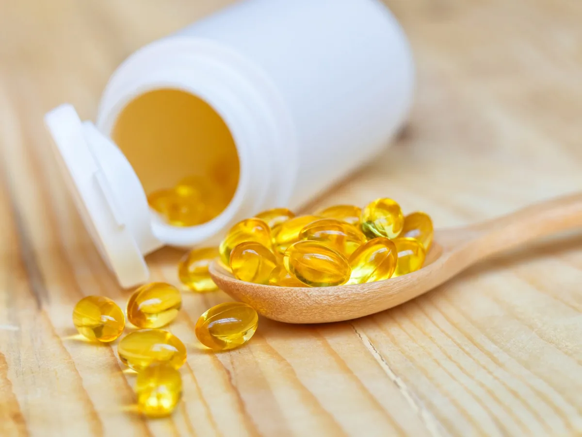Omega-3-Fisch&ouml;l-Kapseln auf Holzl&ouml;ffel