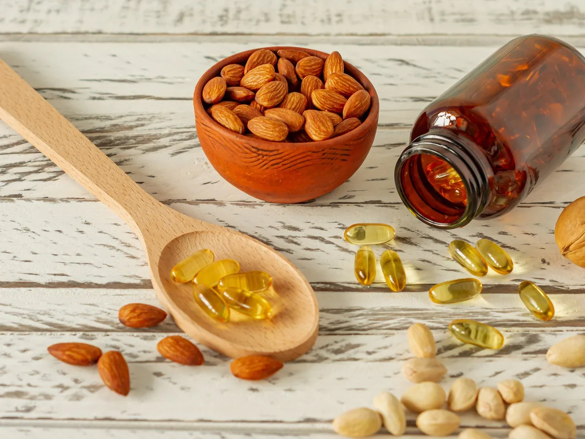 Omega-3-Kapseln neben N&uuml;ssen auf Holz