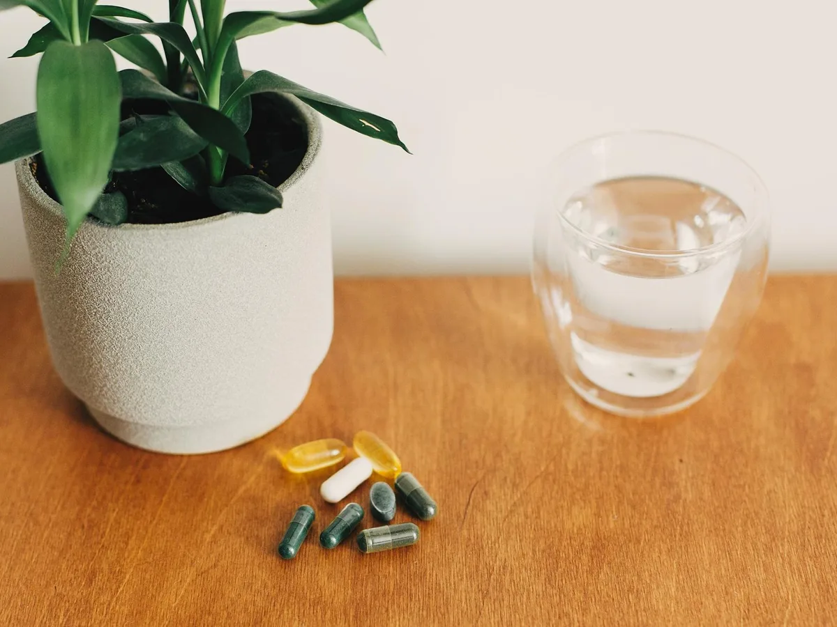 Omega-3-Kapseln und Glas Wasser auf dem Fr&uuml;hst&uuml;ckstisch