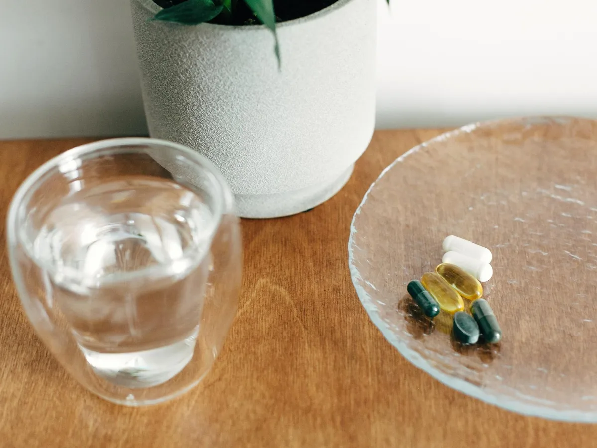 Supplement-Kapseln neben einem Glas Wasser