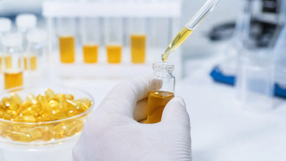 Pipette tropft Fischöl zur Laboranalyse in ein Probenröhrchen