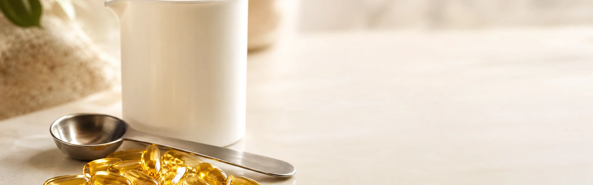 Omega-3-Kapseln neben einem Messlöffel auf hellem Untergrund