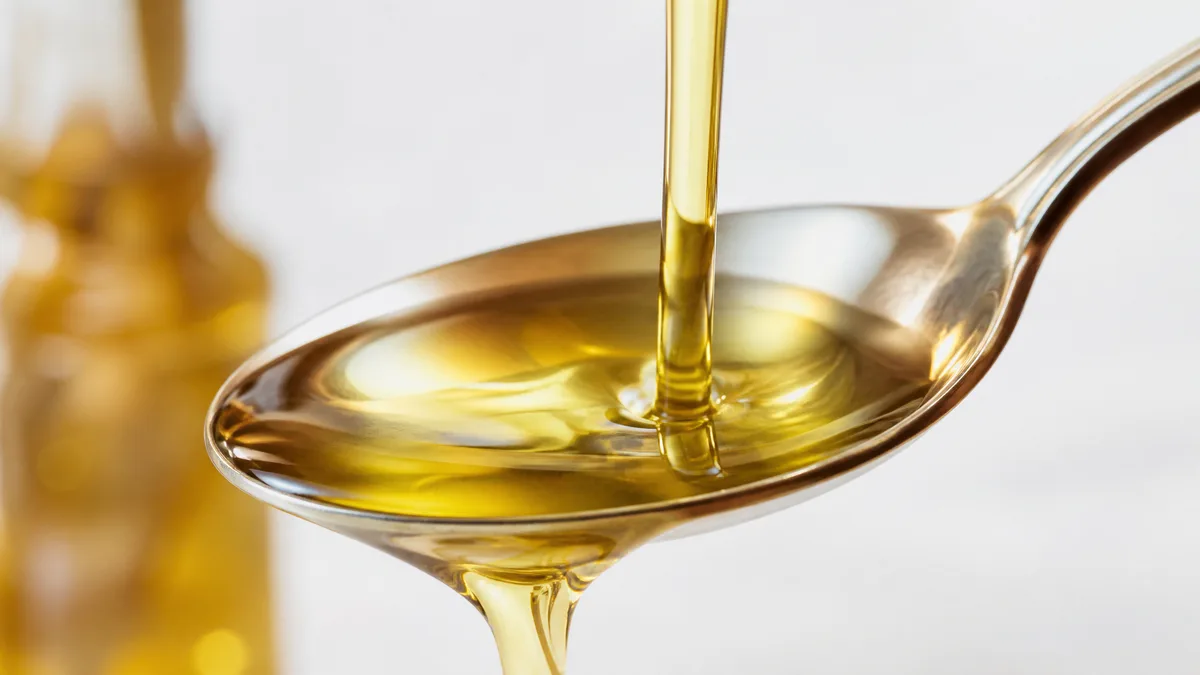 Klares goldenes Omega-3-Öl wird in einen Löffel gegossen